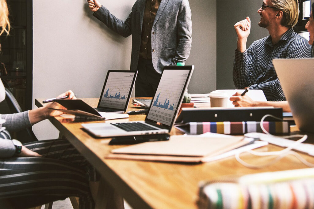 Team di lavoro che discute strategie di digital marketing per il 2024 con grafici e laptop.